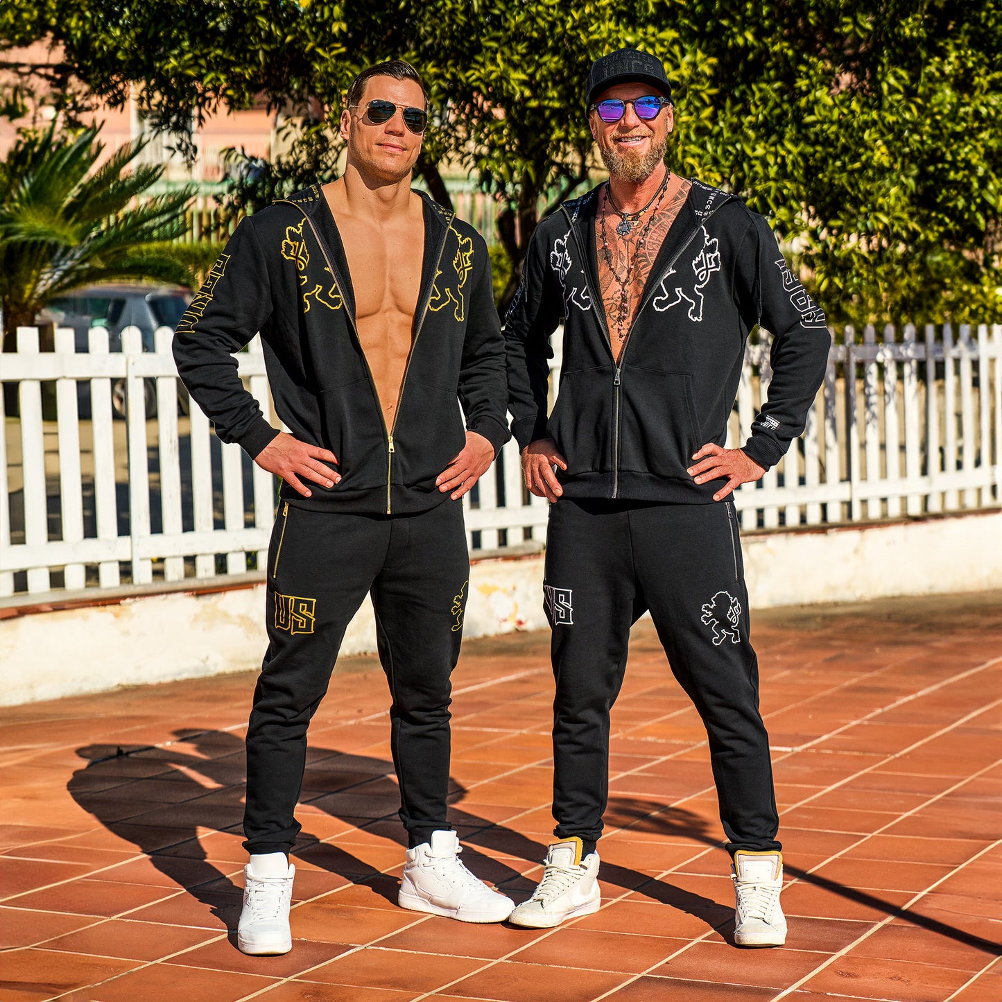 Dva muži s atletickou postavou, na sobě mají černé mikiny UNCS.